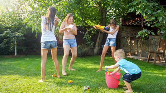 佳得乐喜笑家庭与孩子们在热暑日玩得开心的美丽照片他们有水和花园龙头家庭在夏季玩耍和户外乐喜笑家庭与孩子们在热暑日玩得开心的美丽形象他们背景