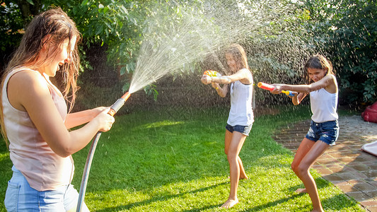 花园软管家庭夏季在户外玩耍和乐家庭夏季在后院玩耍时快乐儿童用水和花园龙头玩耍背景