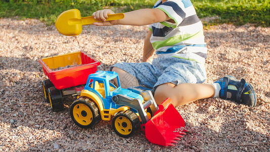 拿铲子挖沙填满玩具卡车的男孩背景图片