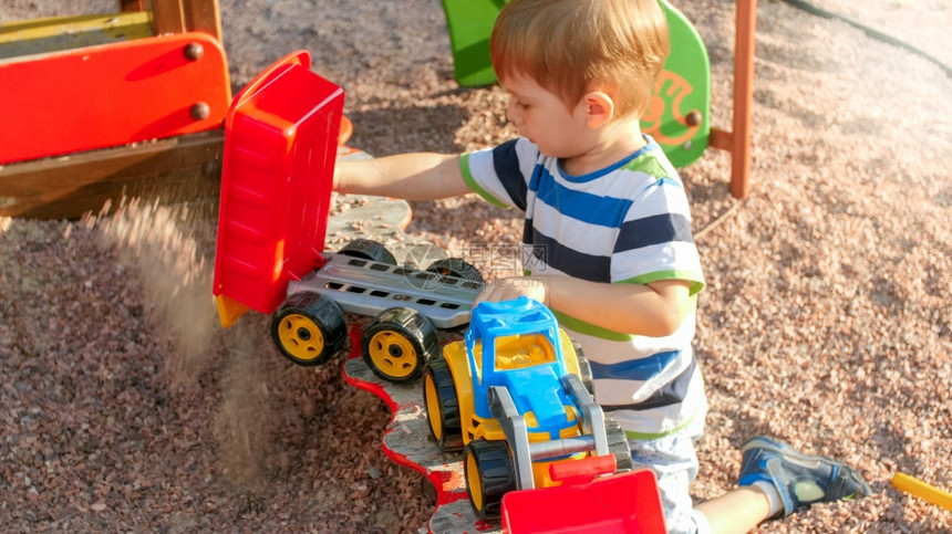 孩子们在公园玩耍和游乐场上快乐笑的小男孩在玩具卡车上用拖扔沙子孩们在公园玩耍和图片