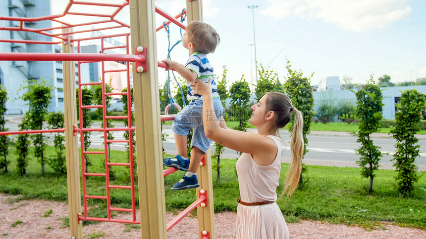 母亲在公园游乐场上扶儿子爬梯子图片