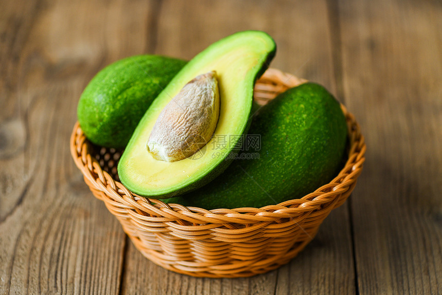 Avocado在木制桌子水果健康食品概念上将一半切成篮子图片