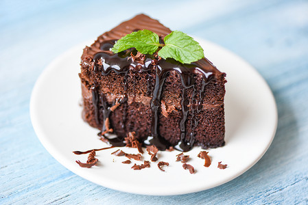 蛋糕巧克力酱美味甜点餐桌上的白盘蛋糕切片巧克力和薄荷叶图片