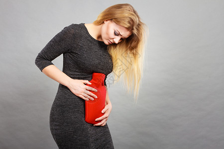 灰色举办女腹部疼痛有热红水瓶卫生保健止痛治疗概念女孩胃痛喝热水瓶背景