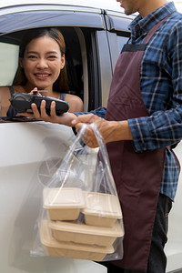 亚洲女客户在接送食品餐饮时将移动支付无接触技术作为流动支付无接触技术在科罗纳新冠virus新冠19大流行后驾车路程更受欢迎背景图片