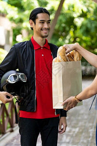 亚洲送货员从面包店拿起杂货袋交给在线订货的客户图片