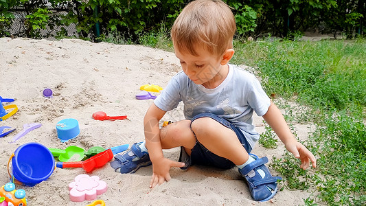 幼儿男孩玩具和在公园沙箱中挖子的肖像图片