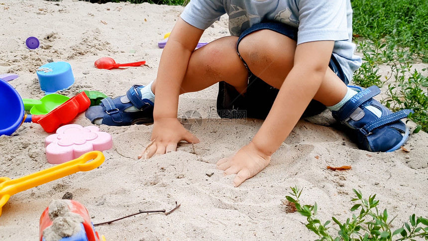 幼儿男孩玩具和在公园沙箱中挖子的肖像图片