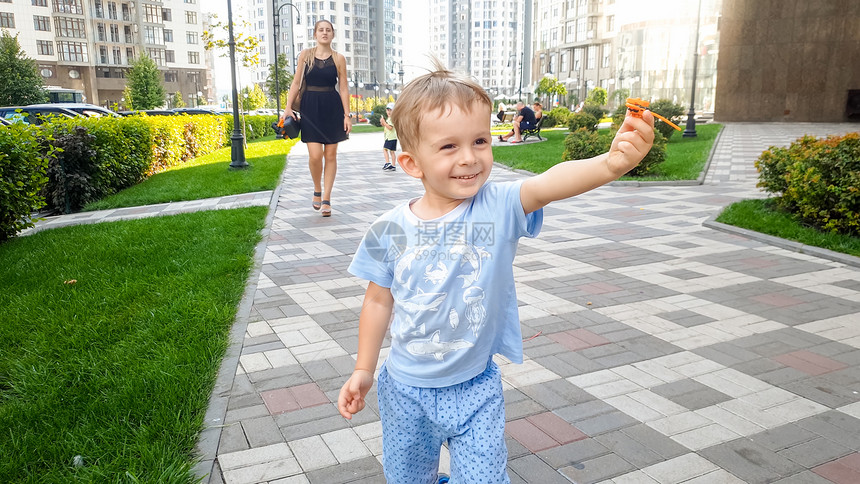 喜笑快乐的幼儿男孩在公园里跑动持有小型塑料玩具直升机孩子们有积极的情绪笑小孩幼儿有快乐笑幼儿男孩在公园里跑动持有小型玩具直升机图片