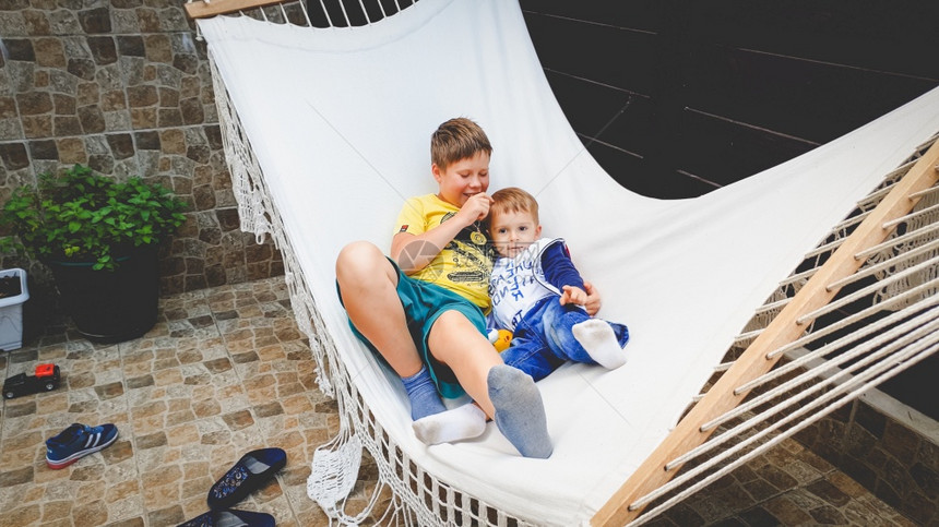 照片来自十几岁男孩与弟一起坐在吊床上和摇摆图片