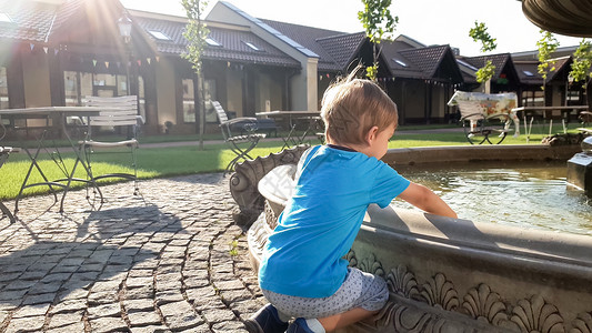 可爱的3岁男孩在公园的喷泉中取水玩高清图片素材