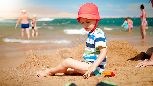坐在海边沙滩上的小男孩图片
