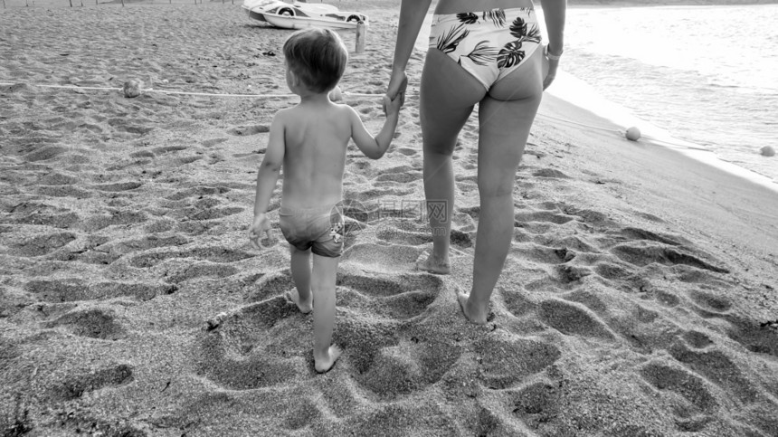 年轻母亲用手抱着小儿子在沙滩上行走的黑人和白照片年轻母亲用手抱着小儿子在沙滩上行走的黑人和白图像年轻母亲用手抱着小儿子在沙滩上行图片