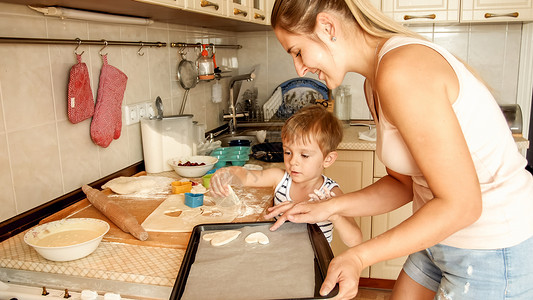 母亲与幼儿男孩的近亲肖像他们握着烘烤锅和厨房做饼干高清图片