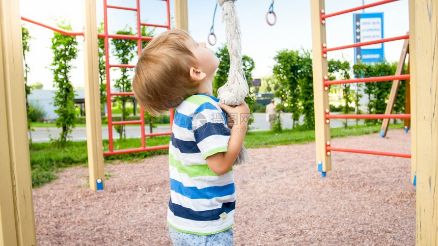 3岁的肖像在操场上玩耍试图爬公园的大绳子图片