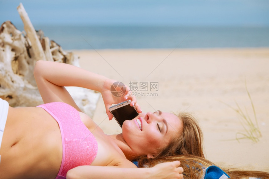 科技与交流快乐的微笑女人手机给朋友打电话年轻有魅力的女孩在海滩上用智能手机说话图片