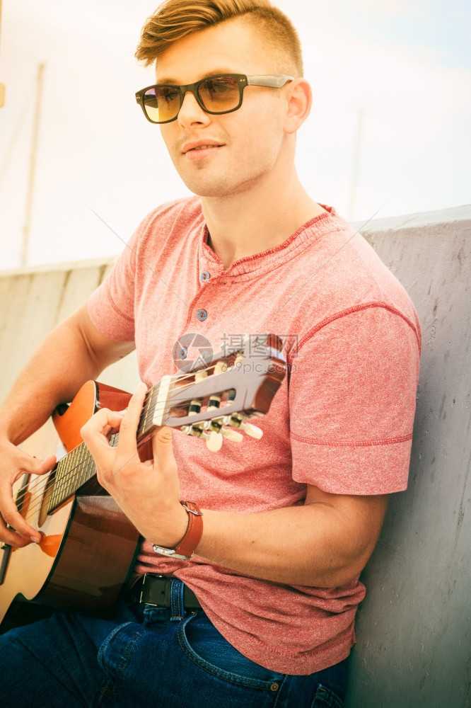 年轻时尚男子穿着太阳眼镜在户外弹经典吉他夏天时间图片