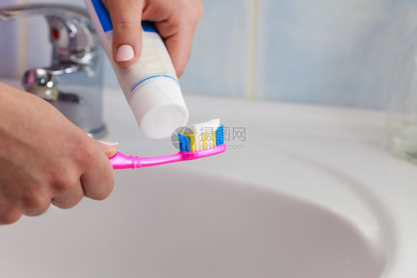 口腔保健手握牙刷和膏手在刷上涂膏图片