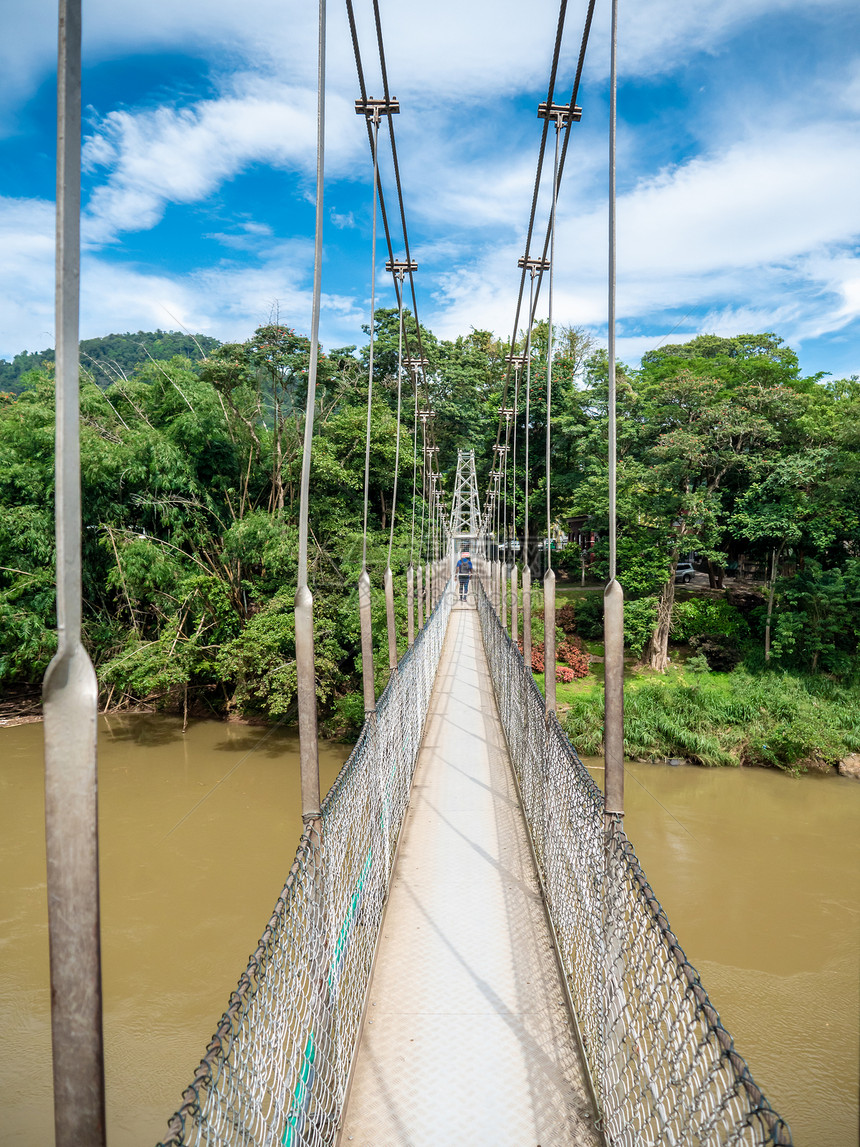 Asian岛热带丛林中危险的旧悬吊桥上行走的照片Asian岛热带丛林中危险的旧悬吊桥上行走的照片图片
