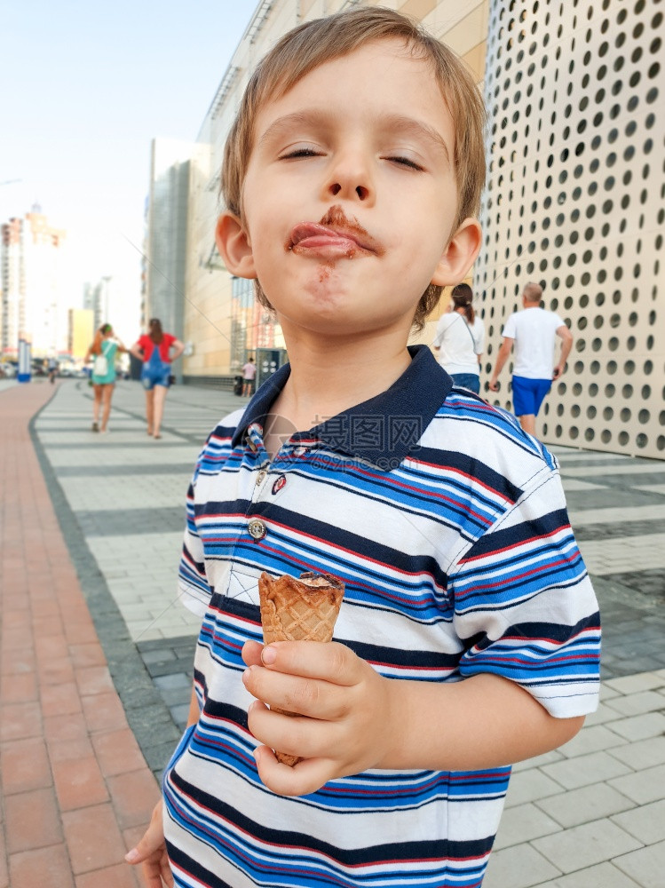 小孩吃巧克力冰淇淋后舔嘴唇的有趣照片图片