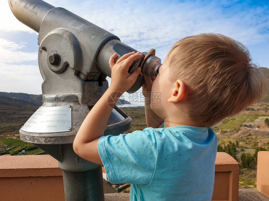 在美丽的山上看硬币操作望远镜的小孩男在美丽的山上看硬币操作望远镜的小孩男肖像图片