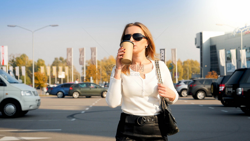 女商人在停车场用纸杯喝咖啡的画像图片