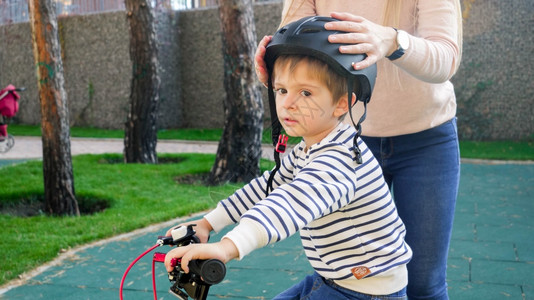 年轻母亲在骑自行车前戴保护头盔年轻母亲骑自行车前戴保护头盔图片