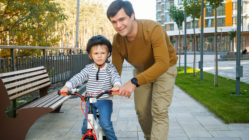 快乐微笑的人教他儿子骑第一辆自行车图片