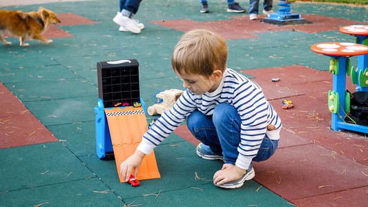 在公园操场玩塑料玩具车的男孩图片