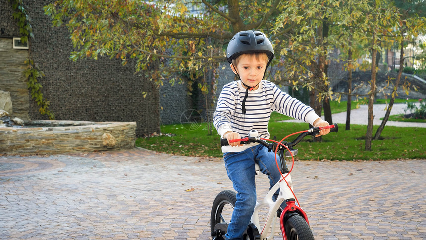 穿着安全头盔骑自行车的可爱小男孩第一次骑自行车的可爱小男孩图片
