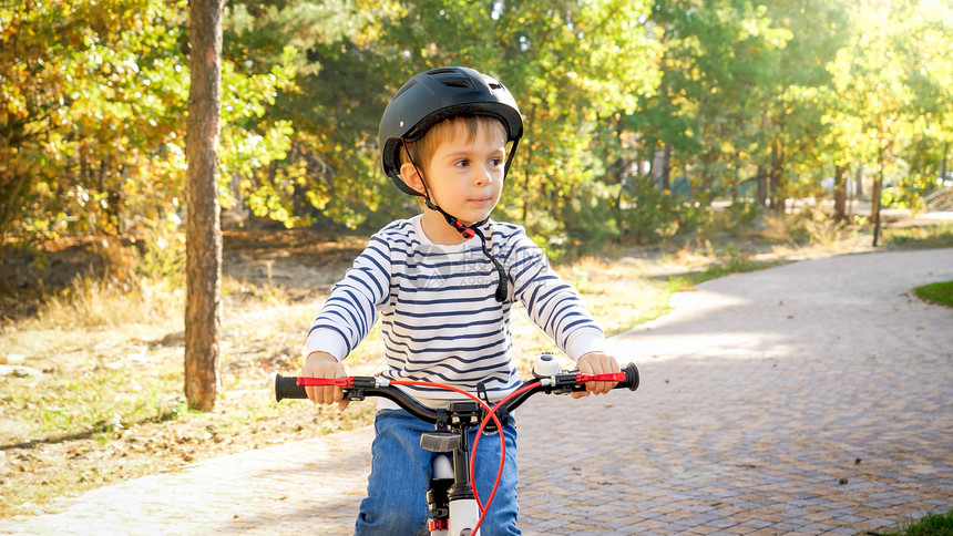 小孩男在公园的路上骑自行车图片