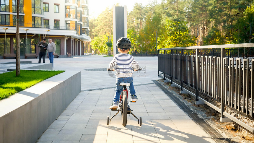 小男孩在阳光明媚的市区街道上骑自行车小男孩在阳光明媚的白天骑自行车小男孩在阳光明媚的街道上骑自行车小男孩在阳光明晴的街道上骑自行图片