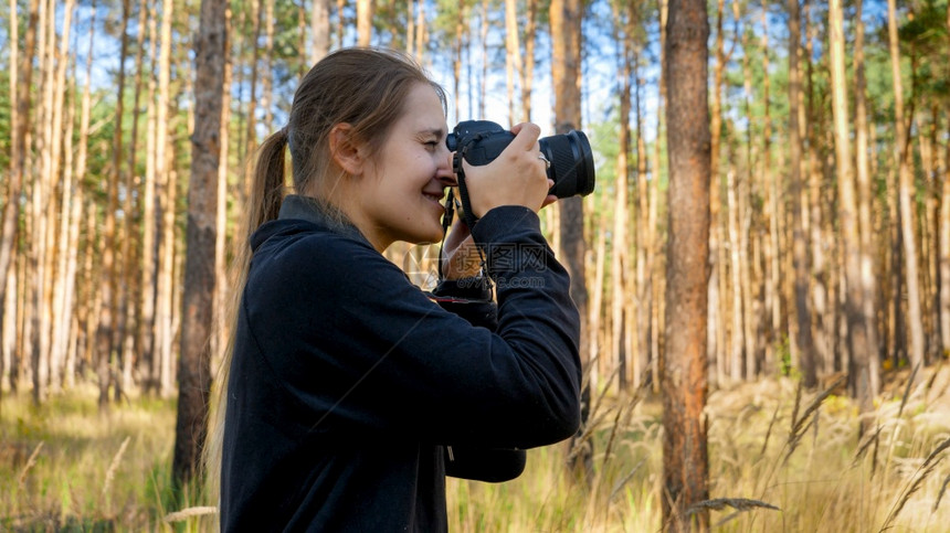 女摄影师在森林用相机拍照图片