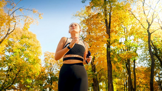 美丽的女孩在秋天的公园跑步运动图片