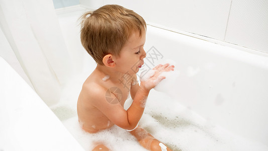 小男孩坐在洗澡和玩肥皂泡沫图片