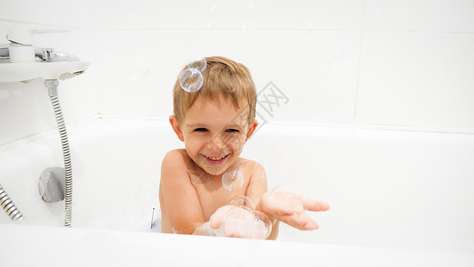 香皂泡沫喜笑的男孩在洗澡时浴和手头上的香皂泡喜笑的男孩在洗澡时浴和手边的香皂泡背景