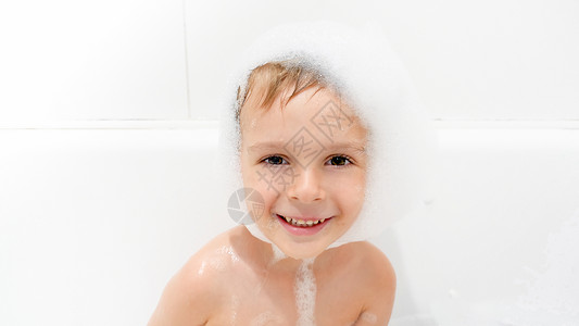 可爱笑的小男孩肖像头顶有肥皂泡沫坐在洗澡和衣时坐在头上图片