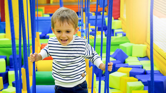 快乐微笑的男孩在游乐公园的场玩耍和爬上绳子图片