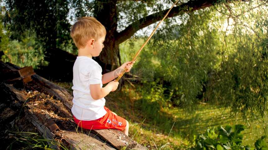 可爱的小男孩在乡下老池塘钓鱼的肖像图片