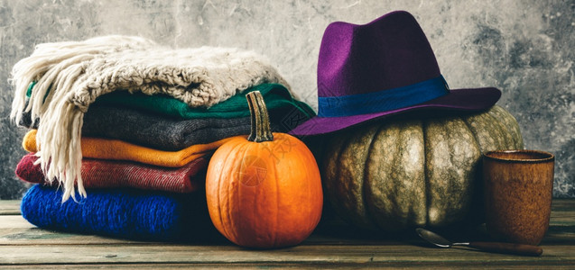 南瓜紫色帽子编织衣服茶杯和木制壶叶子的秋幕背景图片