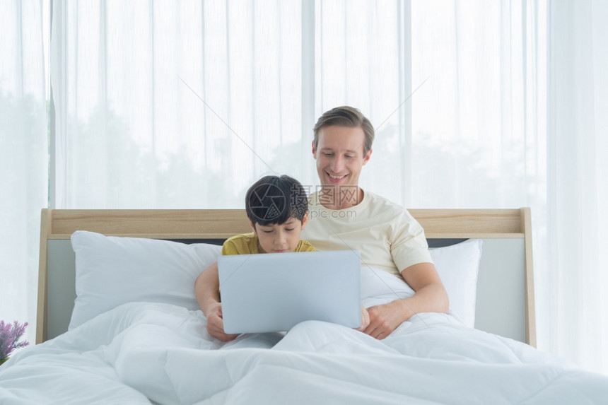 和父亲在床上用笔记本电脑图片
