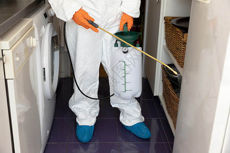灭菌具有防污喷雾器瓶式消毒厨房防护服的人新冠19大流行概念背景