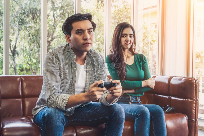 亚洲年轻夫妇有电脑游戏成瘾症家庭问题概念图片