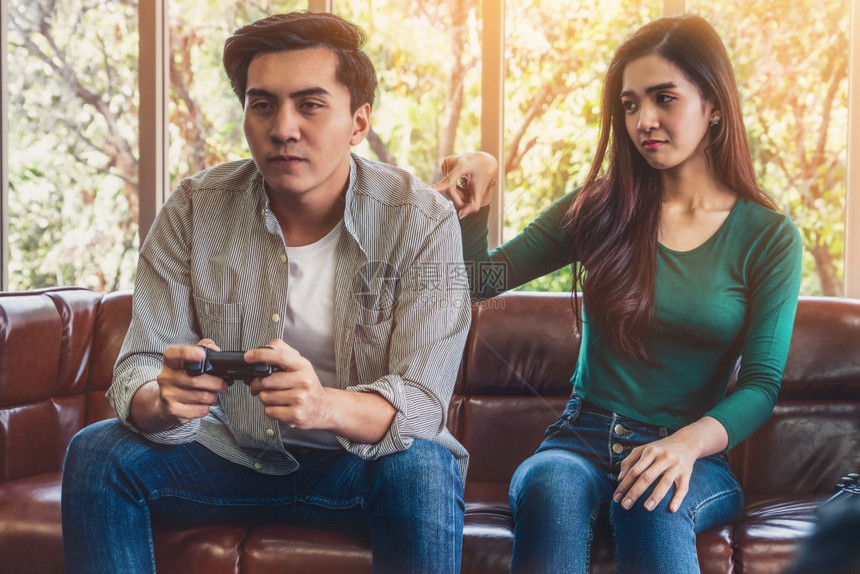 亚洲年轻夫妇有电脑游戏成瘾症家庭问题概念图片