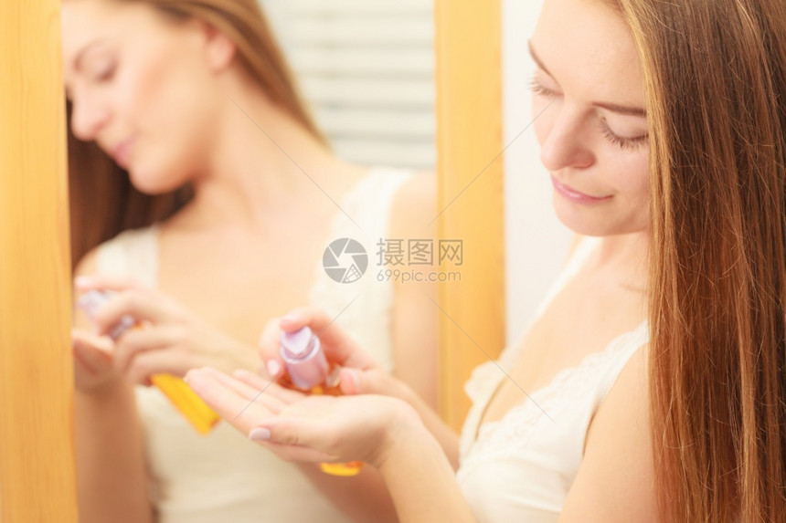 洗手间中妇女用化妆油瓶装着子女孩用奶油化妆品处理长发女孩用化妆油处理长发女孩用润滑油处理长发女孩用奶油处理长发图片