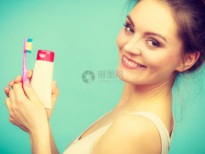 持牙刷和膏洗的妇女带着刷笑的姑娘快乐口腔卫生工作室拍摄绿背景图片
