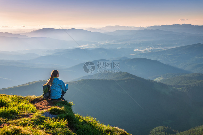 背包的女子坐在山峰上图片