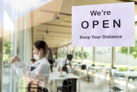为具有亚洲服务员和女背景的新普通餐厅重开放带有社会距离的餐厅标志在开业前准备餐厅背景图片