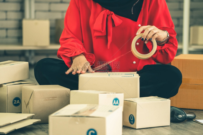 网上销售者在家庭办公室工作将货运箱包装给客户小业主或在因特网上从事电子商务业的企家图片