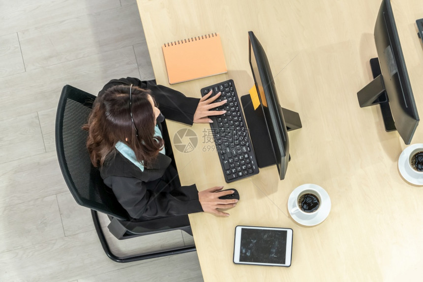 办公室内佩戴顶尖头盔的商界人士与计算机合作支持远程客户或同事呼叫中心电话推销代理服务电话或视频会议图片